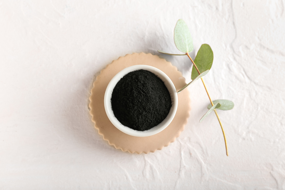 Bowl with Activated Charcoal Tooth Powder on White Background